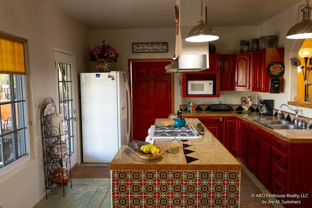 kitchen featuring a sink, decorative light fixtures, a kitchen island, white appliances, and dark brown cabinets