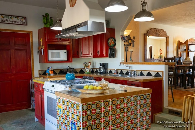 kitchen with white appliances, dark brown cabinets, a sink, a center island, and wall chimney exhaust hood