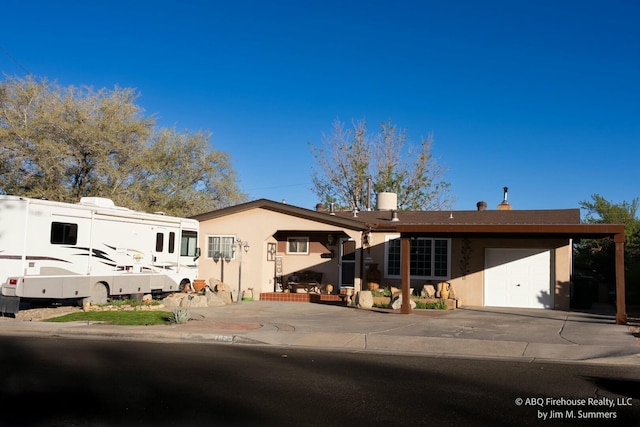 view of front facade with stucco siding, a chimney, concrete driveway, and a garage