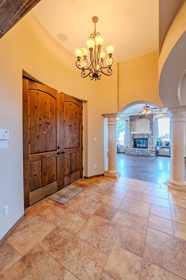 5016 Frontier Rd NE, Rio Rancho, NM 87144 - foyer featuring a stone fireplace, arched walkways, baseboards, decorative columns, and a chandelier