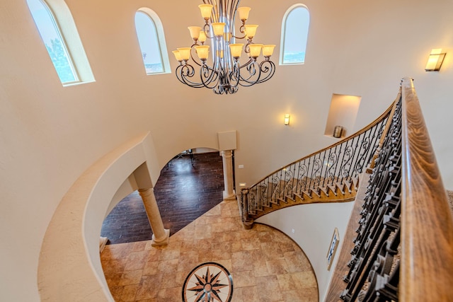 5016 Frontier Rd NE, Rio Rancho, NM 87144 - staircase featuring arched walkways, stone finish floor, a towering ceiling, and an inviting chandelier