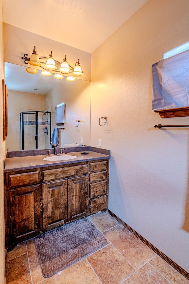 5016 Frontier Rd NE, Rio Rancho, NM 87144 - full bathroom with baseboards, vanity, stone finish flooring, and a stall shower