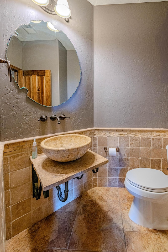 5016 Frontier Rd NE, Rio Rancho, NM 87144 - half bathroom with a textured wall, visible vents, toilet, a sink, and tile walls