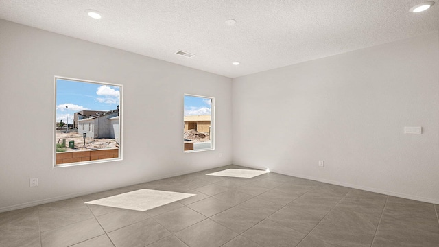 unfurnished room with a textured ceiling, visible vents, baseboards, tile patterned floors, and recessed lighting