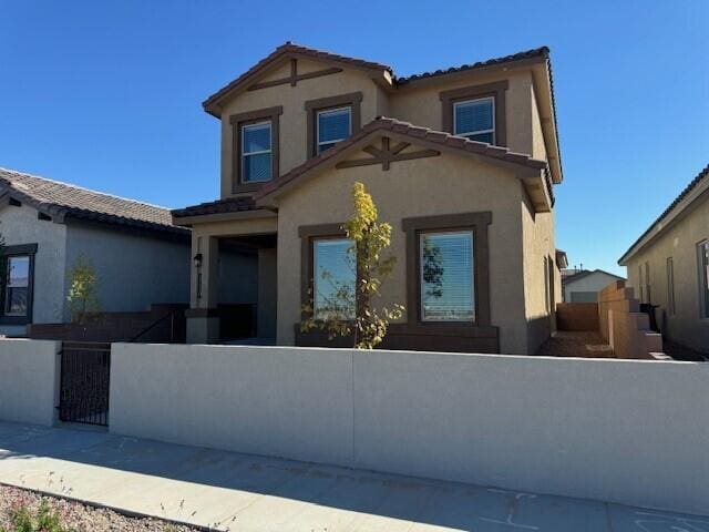view of front of home featuring a gate, a fenced front yard, a tile roof, and stucco siding