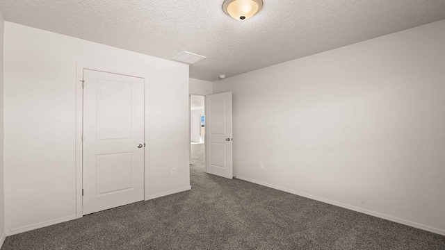 unfurnished bedroom with baseboards, dark colored carpet, and a textured ceiling