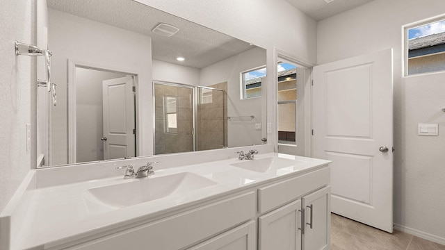 full bathroom featuring a sink, a textured ceiling, a shower stall, and double vanity