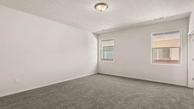 carpeted empty room with visible vents, a textured ceiling, and baseboards