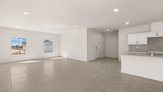 unfurnished living room featuring recessed lighting, a textured ceiling, and light tile patterned flooring