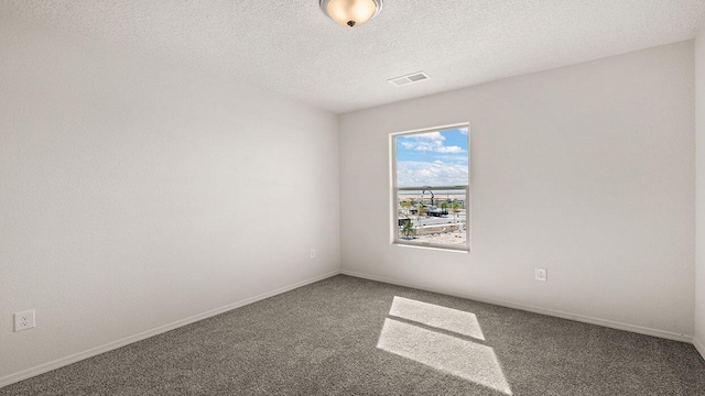 carpeted spare room with a textured ceiling, visible vents, and baseboards
