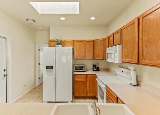 4449 Sunflower Ct SE, Rio Rancho, NM 87124 - kitchen with white appliances, a skylight, brown cabinets, light countertops, and light tile patterned floors