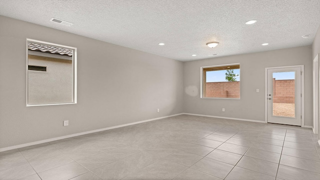 unfurnished room with a textured ceiling, light tile patterned floors, baseboards, visible vents, and recessed lighting