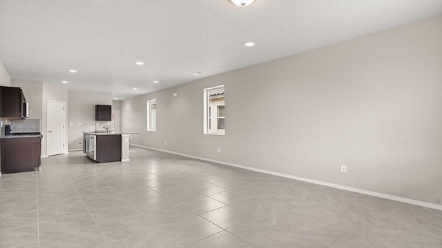 unfurnished living room featuring recessed lighting, a textured ceiling, baseboards, and light tile patterned flooring