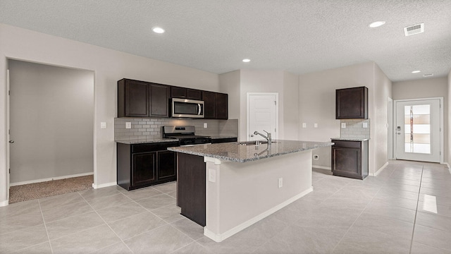 kitchen featuring stainless steel appliances, visible vents, light tile patterned floors, a sink, and decorative backsplash