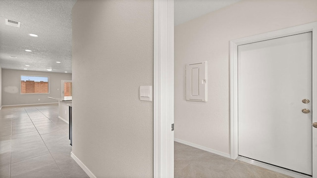 corridor with recessed lighting, visible vents, light tile patterned floors, baseboards, and a textured ceiling