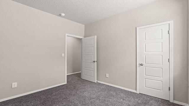 unfurnished bedroom featuring carpet floors, a textured ceiling, and baseboards