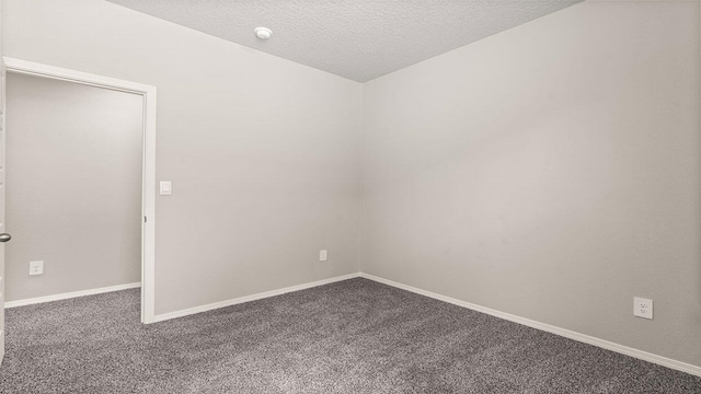 spare room with baseboards, a textured ceiling, and carpet