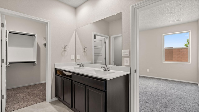 full bathroom with baseboards, a sink, double vanity, and a textured ceiling