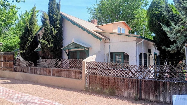 view of front of home with a chimney, stucco siding, and fence