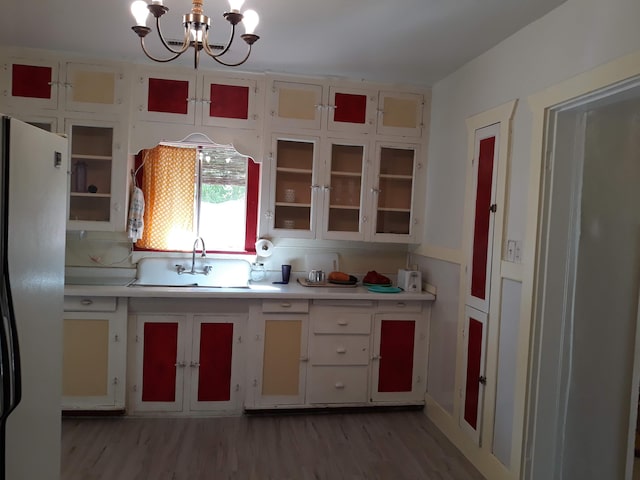 kitchen featuring an inviting chandelier, a sink, freestanding refrigerator, light countertops, and light wood-style floors