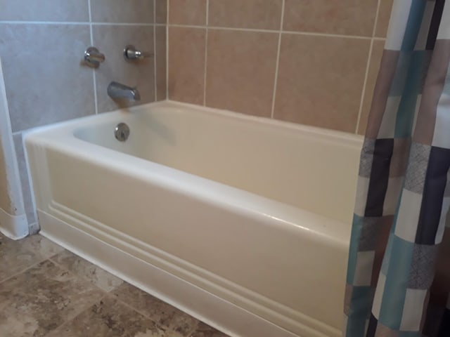 full bathroom with a shower with curtain and a bathtub