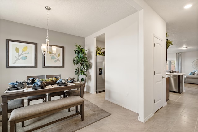 dining space with baseboards, a notable chandelier, a textured ceiling, and light tile patterned floors