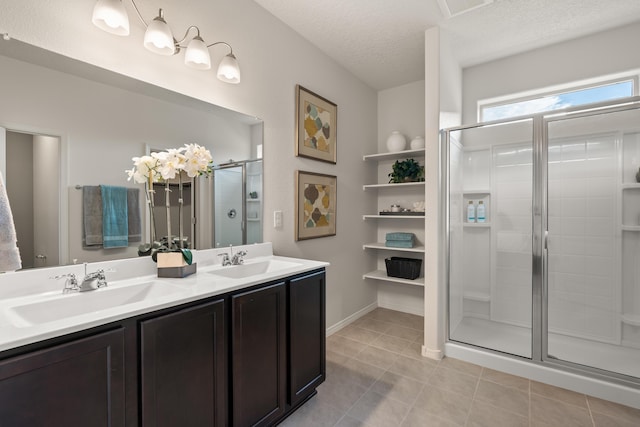 full bathroom featuring a shower stall, a sink, double vanity, and a textured ceiling