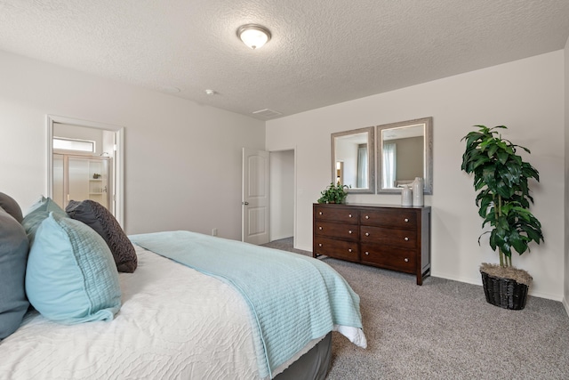carpeted bedroom featuring ensuite bath, baseboards, and a textured ceiling