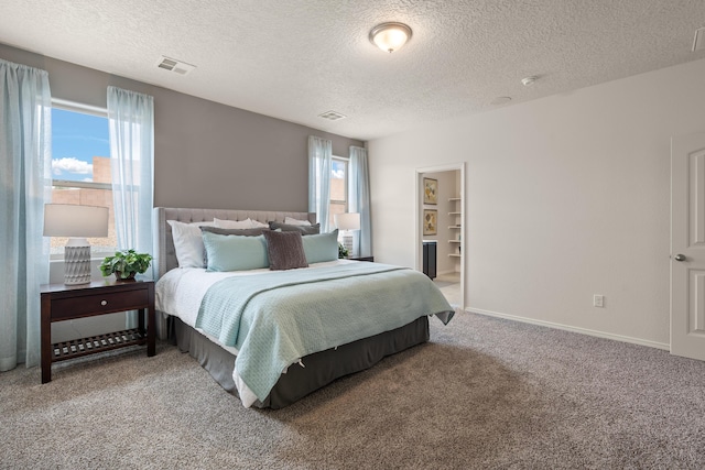 carpeted bedroom featuring baseboards, visible vents, and a textured ceiling