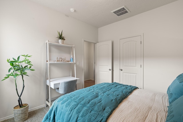 carpeted bedroom featuring baseboards, a textured ceiling, and visible vents