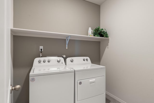 clothes washing area featuring washing machine and dryer, baseboards, and laundry area