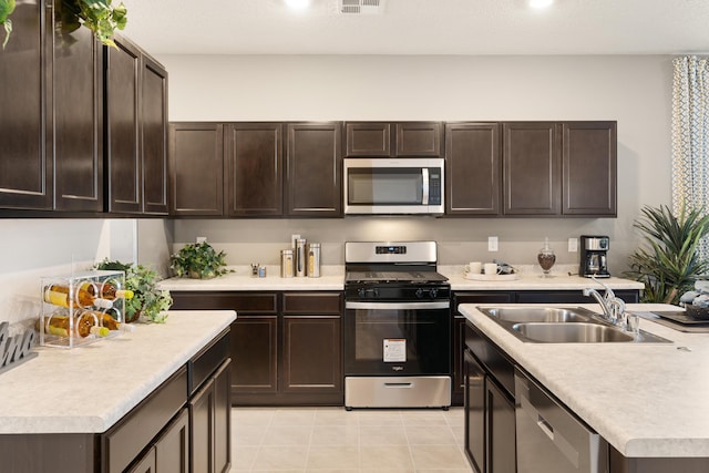 kitchen featuring dark brown cabinetry, appliances with stainless steel finishes, a sink, and light countertops