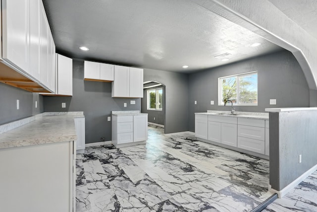 kitchen with marble finish floor, arched walkways, a sink, and plenty of natural light