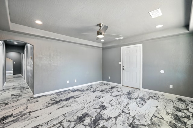 spare room featuring a ceiling fan, baseboards, arched walkways, and marble finish floor