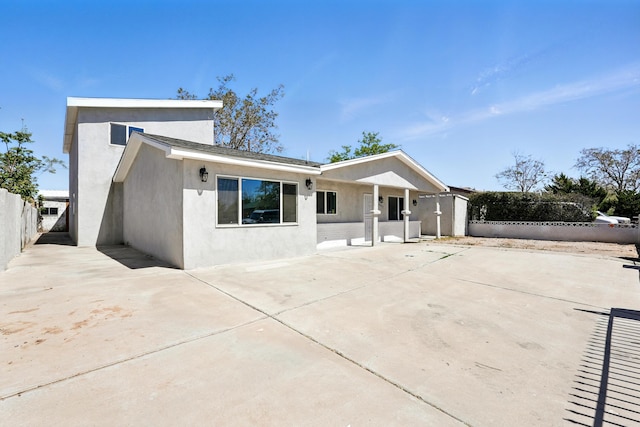 rear view of property featuring stucco siding, a patio, and fence