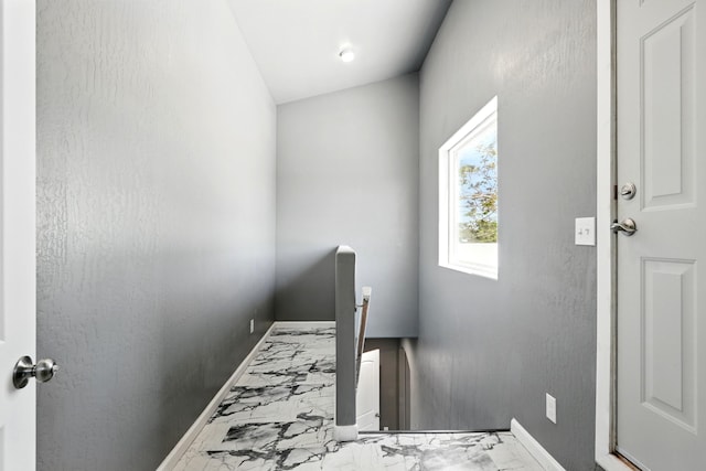 staircase with marble finish floor and baseboards