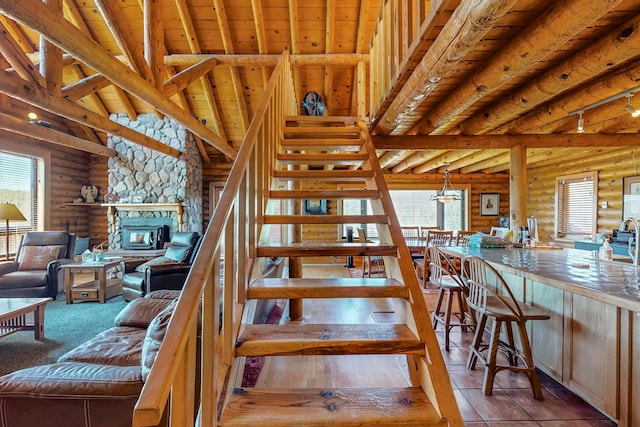 387 County Rd B64, Pecos, NM 87552 - stairs featuring log walls, plenty of natural light, wood ceiling, and a stone fireplace