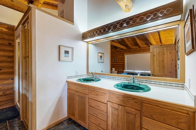 387 County Rd B64, Pecos, NM 87552 - bathroom featuring log walls, baseboards, beamed ceiling, double vanity, and wood ceiling