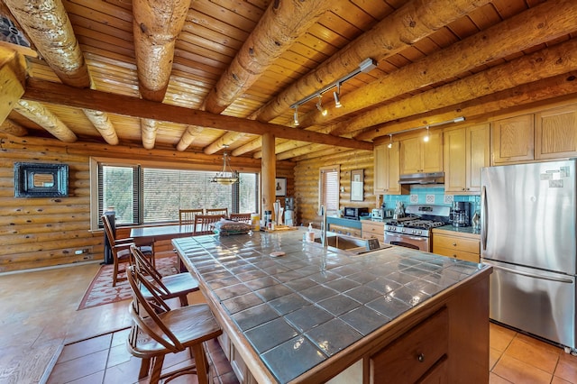 387 County Rd B64, Pecos, NM 87552 - kitchen featuring stainless steel appliances, tile countertops, log walls, a sink, and under cabinet range hood