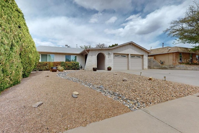 single story home with concrete driveway, an attached garage, and brick siding
