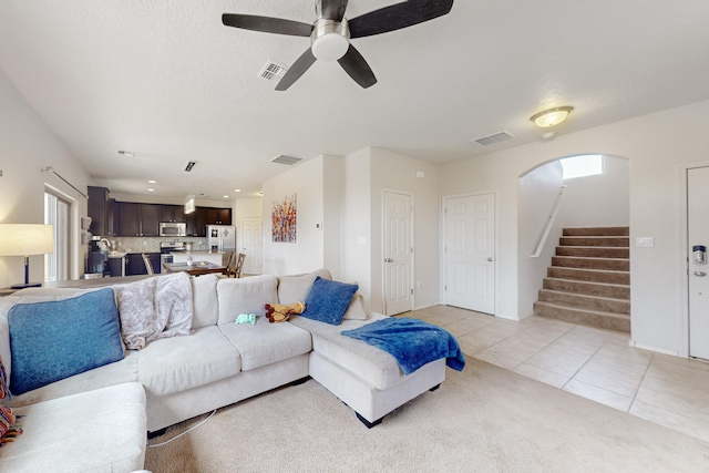 7105 Napoleon Rd NE, Rio Rancho, NM 87144 - living room featuring light tile patterned floors, stairs, a ceiling fan, arched walkways, and light colored carpet
