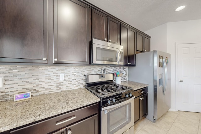 7105 Napoleon Rd NE, Rio Rancho, NM 87144 - kitchen featuring stainless steel appliances, dark brown cabinets, tasteful backsplash, light tile patterned floors, and light stone counters