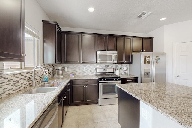 7105 Napoleon Rd NE, Rio Rancho, NM 87144 - kitchen with appliances with stainless steel finishes, a sink, dark brown cabinetry, light stone counters, and recessed lighting
