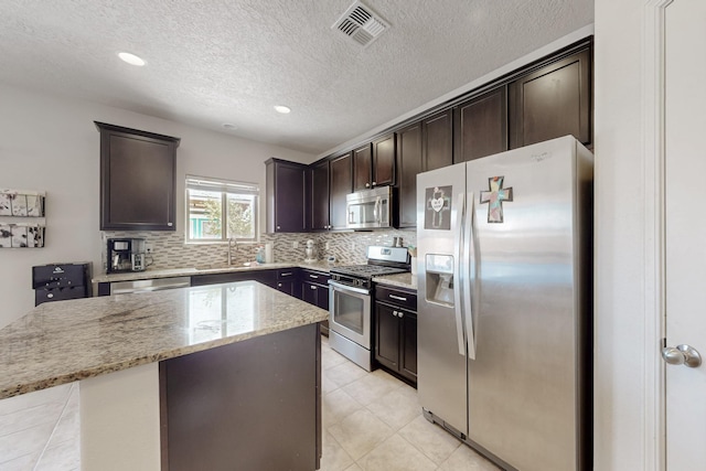 7105 Napoleon Rd NE, Rio Rancho, NM 87144 - kitchen featuring stainless steel appliances, a center island, a sink, tasteful backsplash, and dark brown cabinets