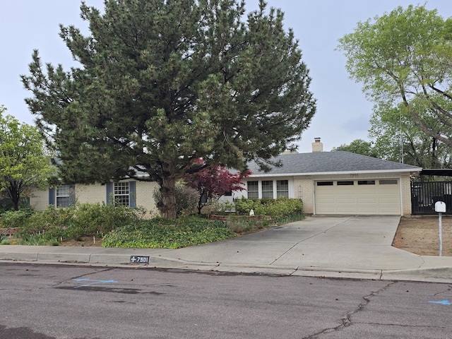 view of front facade featuring a chimney, brick siding, driveway, and a garage
