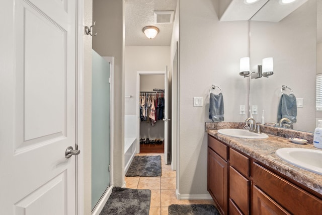 5668 Cold Creek Ave NW, Albuquerque, NM 87114 - full bath with an enclosed shower, tile patterned floors, double vanity, a spacious closet, and a textured ceiling