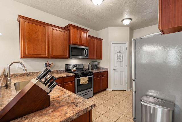 5668 Cold Creek Ave NW, Albuquerque, NM 87114 - kitchen featuring stainless steel appliances, light tile patterned floors, brown cabinets, a textured ceiling, and a sink
