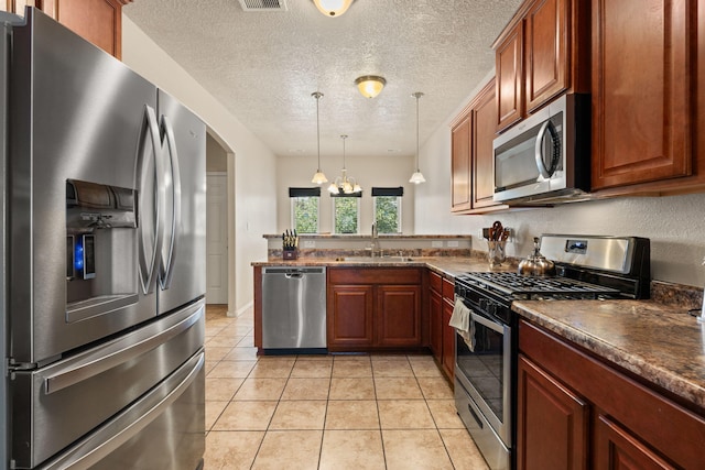 5668 Cold Creek Ave NW, Albuquerque, NM 87114 - kitchen featuring appliances with stainless steel finishes, a sink, a peninsula, decorative light fixtures, and light tile patterned floors