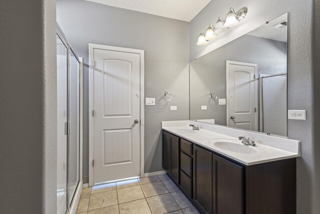 bathroom featuring a stall shower, tile patterned flooring, and a sink