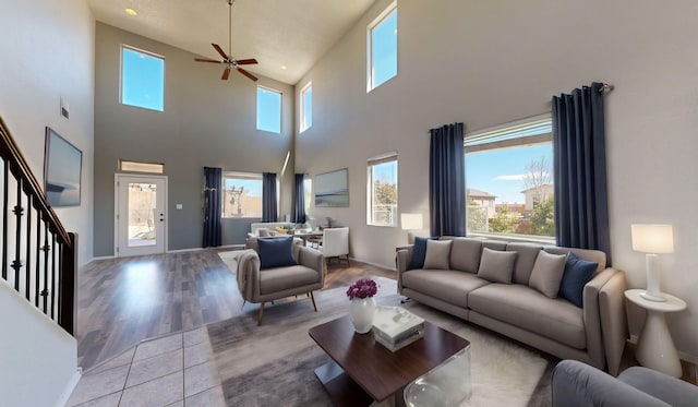 living area featuring a towering ceiling, stairway, a wealth of natural light, and wood finished floors